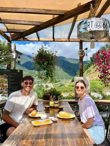 Un uomo e una donna seduti su un tavolo di legno di The Chill Garden Sapa a Sa Pa