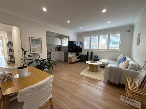 a living room with a couch and a table at Coogee Sunrise 2 Bed Apt with Parking, Work Desks & Balcony in Sydney