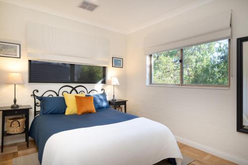 a bedroom with a bed with blue and yellow pillows at Alderwood Cottage - Heart of The Highlands in Glenquarry