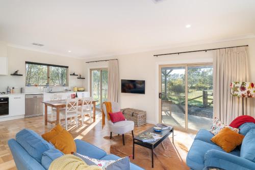 a living room with two blue couches and a kitchen at Alderwood Cottage - Heart of The Highlands in Glenquarry