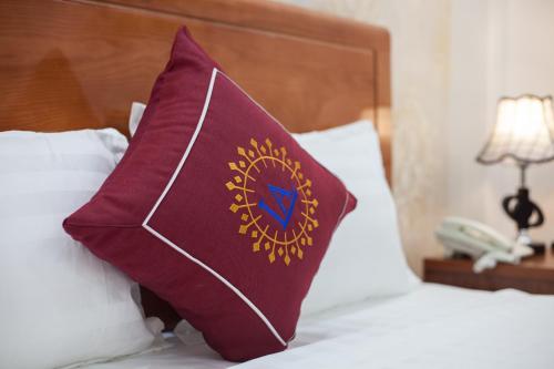 a burgundy pillow sitting on top of a bed at Luxury Airport Hotel - Convenient & Friendly in Hanoi