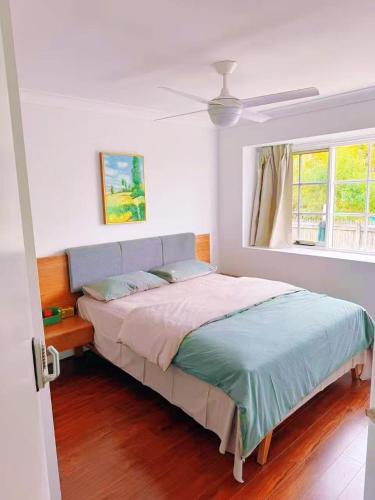 a bed in a white room with a window at Yaka room in Brisbane