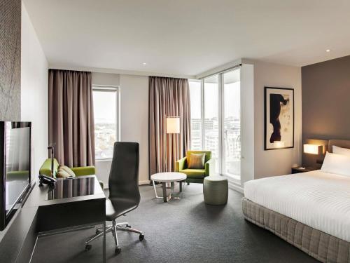 a hotel room with a bed and a desk at Pullman Adelaide in Adelaide