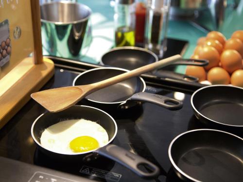 a stove top with pans with an egg in them at Novotel Chennai Chamiers Road in Chennai
