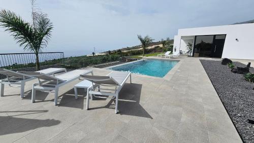 Un patio con mesa y sillas junto a una piscina. en Casa Laina, en Tijarafe