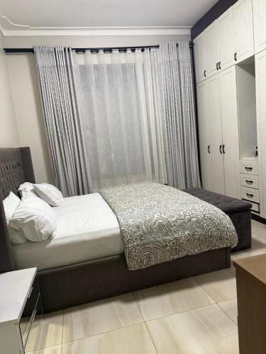 a bedroom with a bed and a window with curtains at Ahwera beautiful homes in Kampala