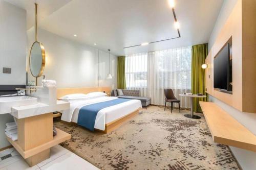 a bedroom with a bed and a sink and a mirror at Borrman Hotel Jining High-tech Huangtun in Jining