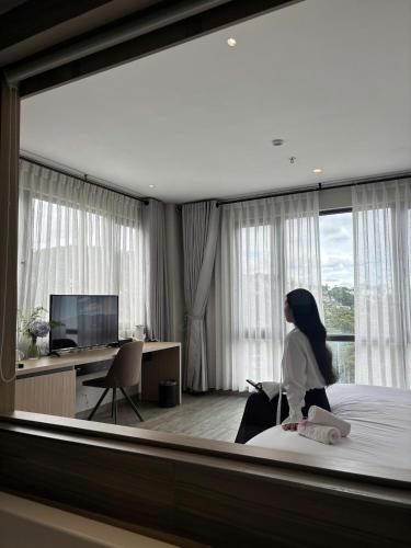 a woman sitting on a bed in a hotel room at The Luxe Da Lat in Da Lat
