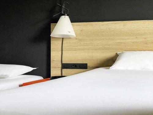 a bedroom with two white beds and a lamp at Ibis Styles Crolles Grenoble A41 in Crolles