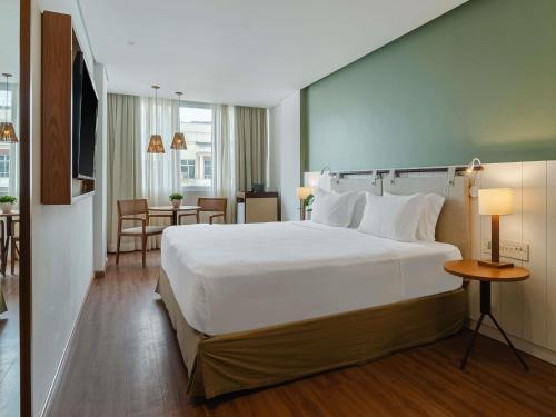 a hotel room with a large bed and a table at Grand Mercure Rio de Janeiro Copacabana in Rio de Janeiro