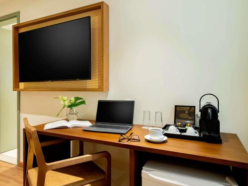 a desk with a laptop and a television on it at Grand Mercure Rio de Janeiro Copacabana in Rio de Janeiro