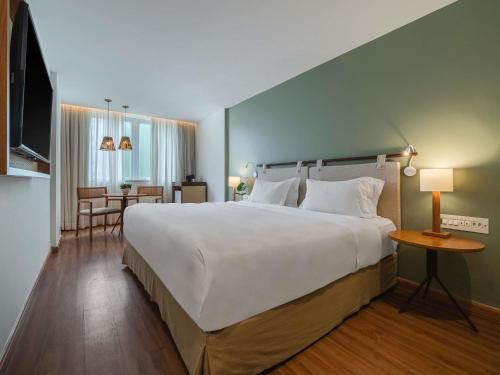 a bedroom with a large white bed and a table at Grand Mercure Rio de Janeiro Copacabana in Rio de Janeiro