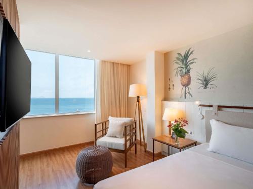 a hotel room with a bed and a chair and a window at Grand Mercure Rio de Janeiro Copacabana in Rio de Janeiro