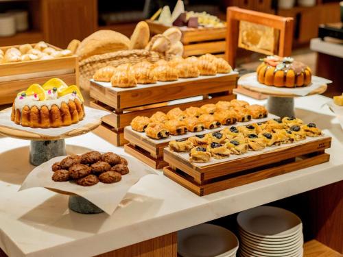 a table filled with different types of pastries and desserts at Grand Mercure Rio de Janeiro Copacabana in Rio de Janeiro