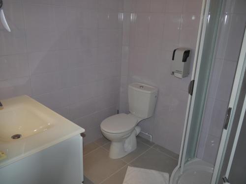 a white bathroom with a toilet and a shower at Logis Hotel Des Voyageurs Restaurant La Bonne Tabl'Hay in Livron-sur-Drôme