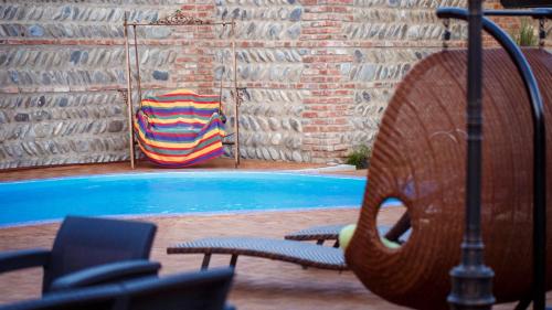 a swimming pool with a chair and a swimming pool at Hotel Gino Wellness Mtskheta in Mtskheta