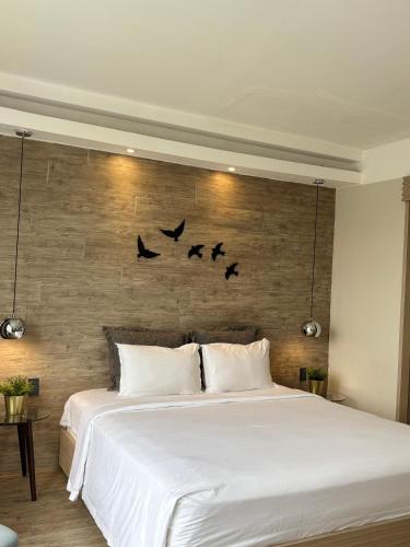 a bedroom with a white bed with birds on the wall at The Luxe Da Lat in Da Lat