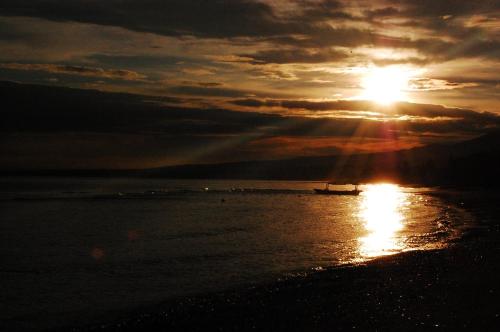 a boat in the ocean with the sun in the sky at Beachfront Villa Jepun Segara in Banjar