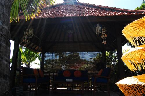 a wooden gazebo with chairs and a table at Beachfront Villa Jepun Segara in Banjar