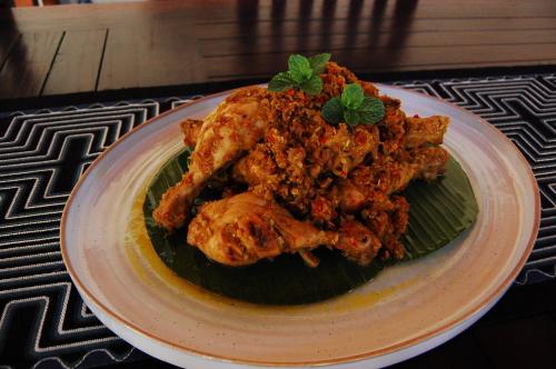 a plate of food with chicken on a green leaf at Beachfront Villa Jepun Segara in Banjar