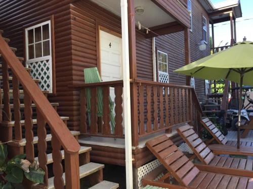 a wooden cabin with stairs and an umbrella at Blue Wave Guest House in Caye Caulker