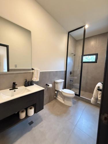 a bathroom with a sink and a toilet and a mirror at Oceanfront - Villa Catalina - Beach House in Tela