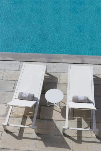 two white chairs and a table next to a pool at OZADI Tavira Hotel in Tavira