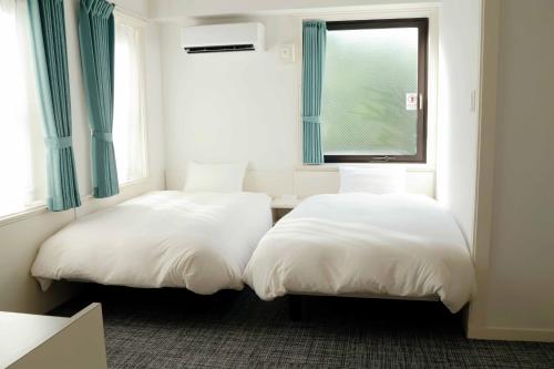 two white beds in a room with a window at Hananoie華之家 in Tokyo