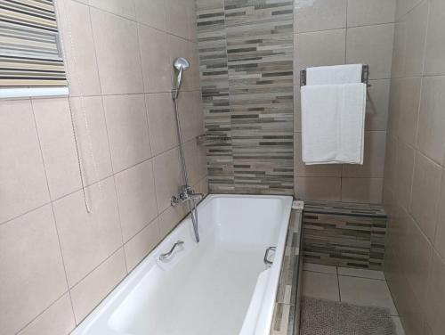 a white bath tub in a bathroom with a shower at Long on Hill in Johannesburg
