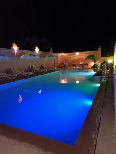a swimming pool at night with blue illumination at Domaine JJ in Marrakech