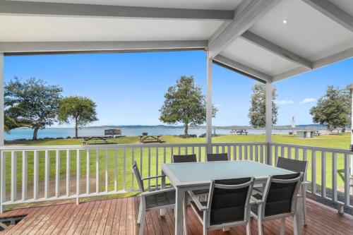 a screened porch with a table and chairs and a view of the ocean at Ingenia Holidays Eden Beachfront in Eden