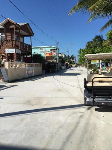 a golf cart driving down a street next to a building at Blue Wave Guest House in Caye Caulker