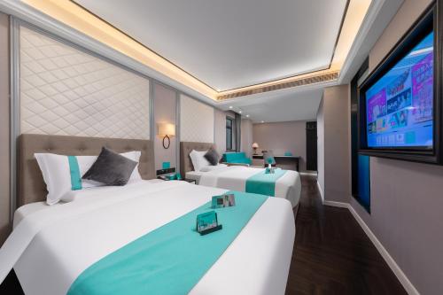 a hotel room with two beds and a flat screen tv at 希岚酒店广州富力海珠城店&地铁直达展馆 in Guangzhou