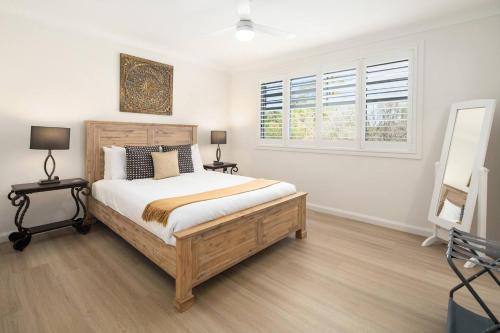 a bedroom with a large bed and two windows at Drift & Dwell - Minutes to Labrador Beach & Dining in Gold Coast