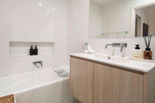 a white bathroom with a sink and a bath tub at Drift & Dwell - Minutes to Labrador Beach & Dining in Gold Coast