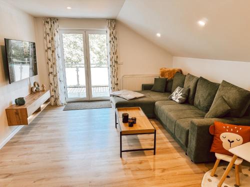 a living room with a green couch and a table at Bachgeflüster-Suite in Bad Koetzting