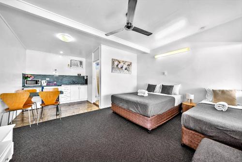 a bedroom with two beds and a desk and a kitchen at Pearly Shell Motel in Bowen
