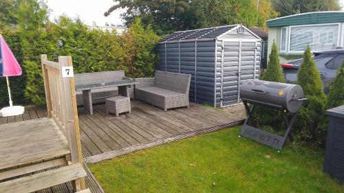 a backyard with a grill and a bench on a deck at Chalet Meerwijck mit Terrasse am Wasser und Meer mit Schwimmbad in Kropswolde