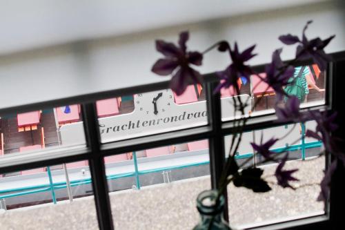 une fenêtre avec un vase et des fleurs violettes dans l'établissement Wolf Hotel Kitchen & Bar, à Alkmaar