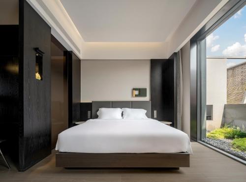 a bedroom with a white bed and a large window at Lezhizhi Anyu Hotel, Zhuge Liang Plaza, Wanda Branch in Xiangyang