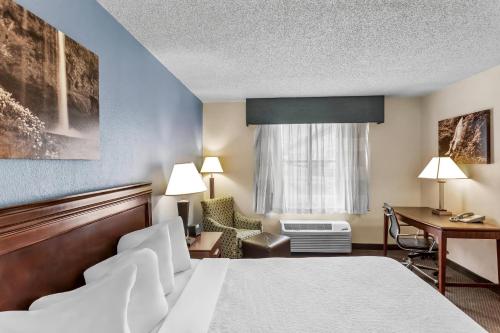a hotel room with a bed and a desk at Rodeway Inn in Barboursville