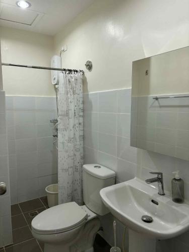 a white bathroom with a toilet and a sink at Mactan Plains Studio Unit in Punta Engaño