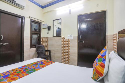 a bedroom with a bed and two doors and a chair at FabExpress Kanha Dhaam in Kānpur