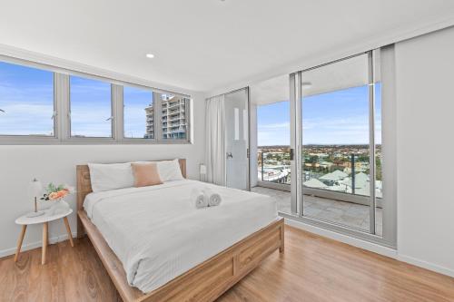 a bedroom with a large bed and large windows at Northwind Beachfront Apartments in Mooloolaba