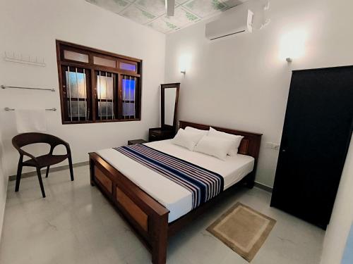 a bedroom with a bed with a chair and a window at Freedom-Inn Resort Villa in Tangalle