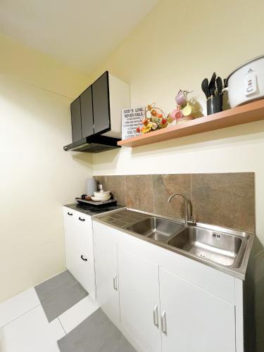 a kitchen with white cabinets and a sink at CoZerenity Stays Minimalist Condo in Naga City in Naga