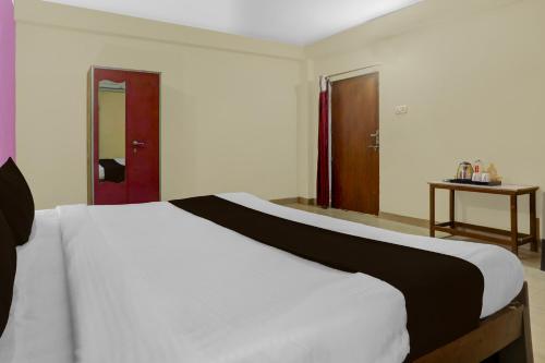a bedroom with a white bed and a wooden door at Hotel O BABA GUEST HOUSE in Shivāpur