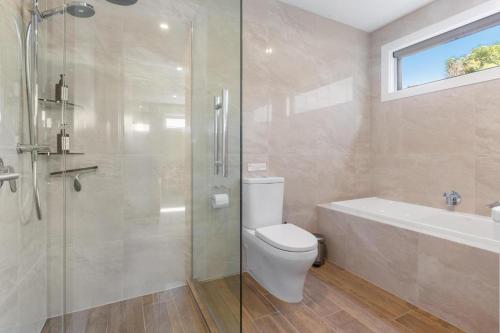 a bathroom with a shower and a toilet and a bath tub at Aston Road Villa Bed & Breakfast in Waikanae