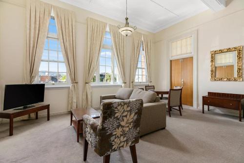 a living room with a couch and a tv at Quality Hotel Regent Rockhampton in Rockhampton
