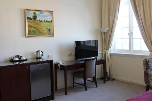 a room with a desk with a computer and a television at Quality Hotel Regent Rockhampton in Rockhampton